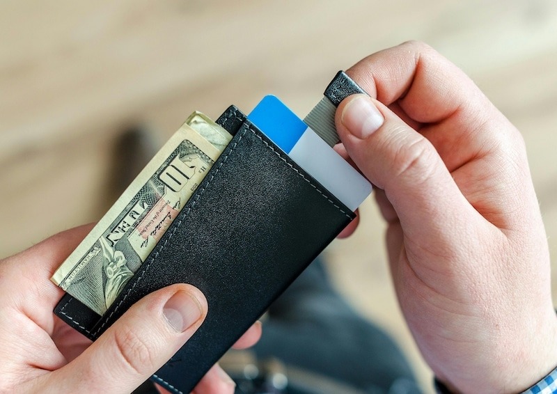 Hombre sosteniendo una billetera abierta con dinero en su interior.