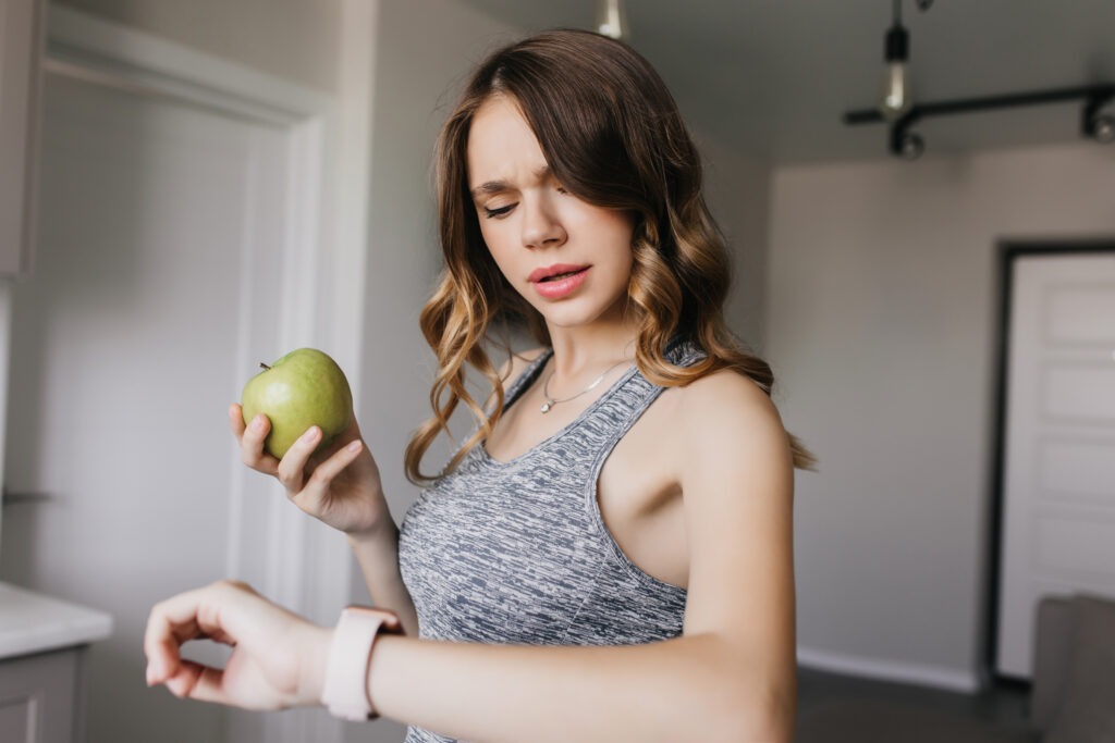 Mujer revisando su smartwatch y alimentación saludable para controlar el estrés y mantener hábitos sanos.