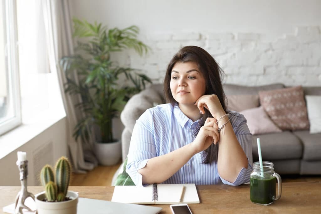 Mujer sentada en casa reflexionando sobre el estrés y el impacto del cortisol en el bienestar diario.