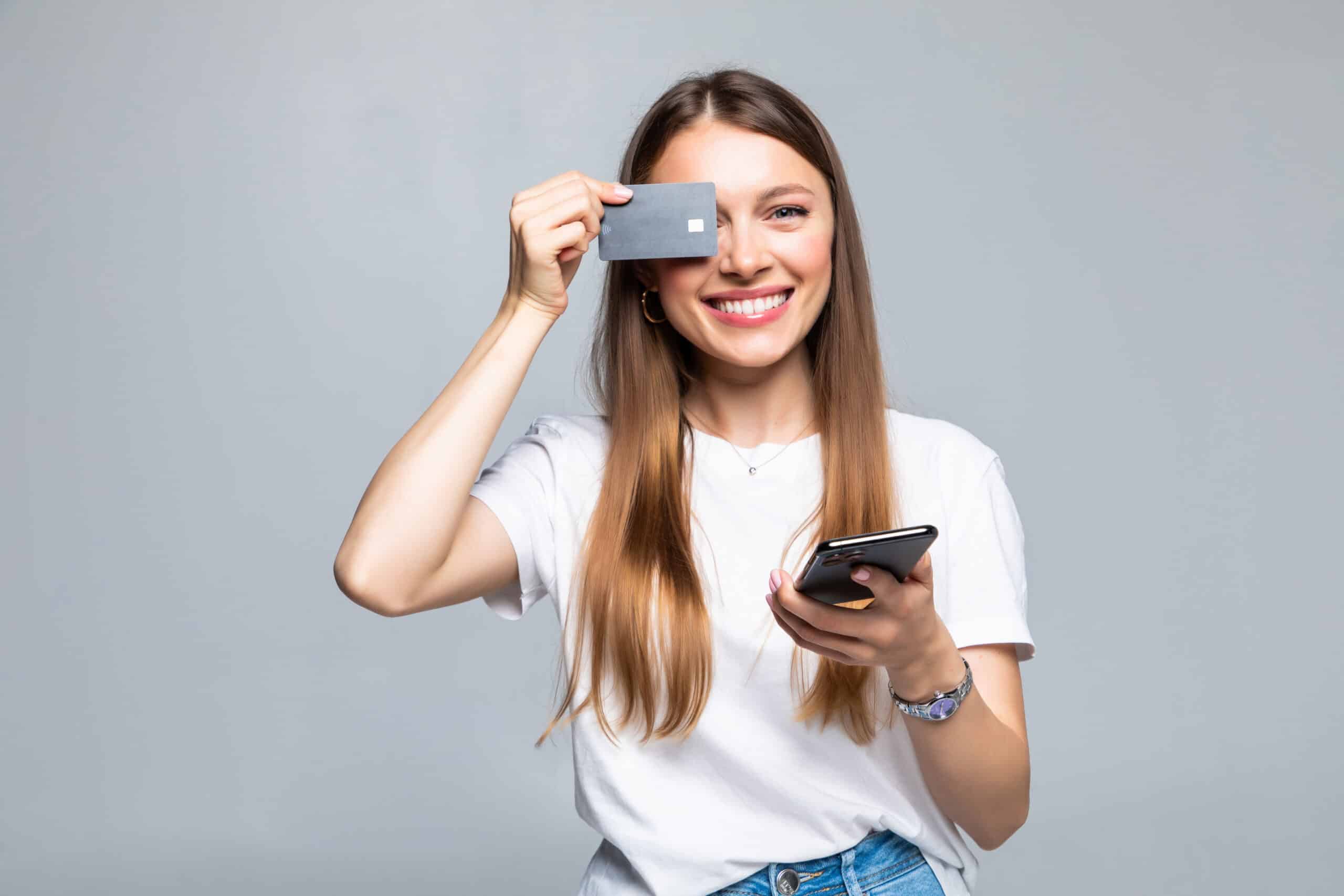 Mujer sonriente sosteniendo una tarjeta de crédito, mostrando satisfacción y confianza.