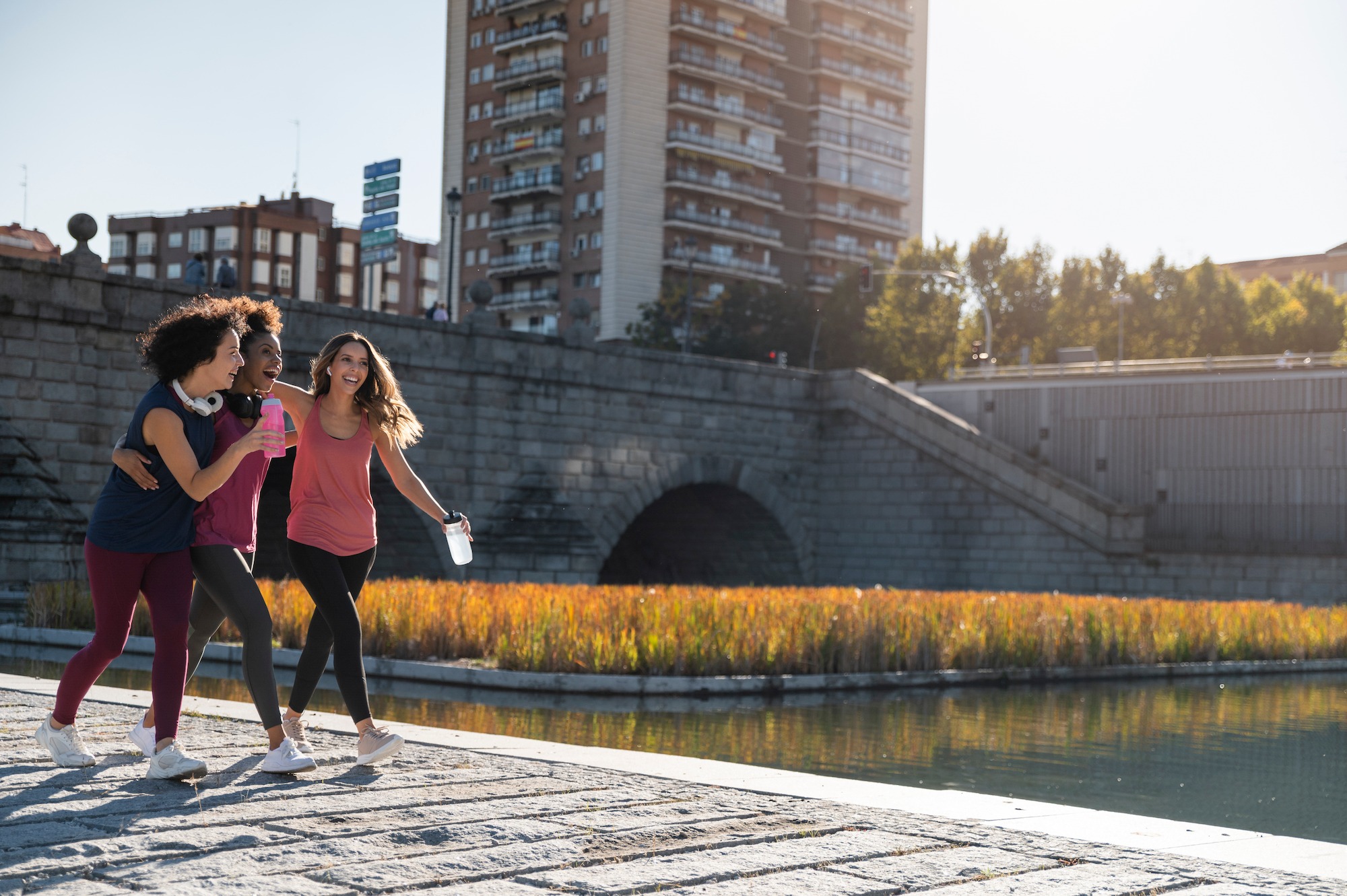Tres mujeres caminando por un sendero junto a un río, disfrutando del paisaje y la compañía.